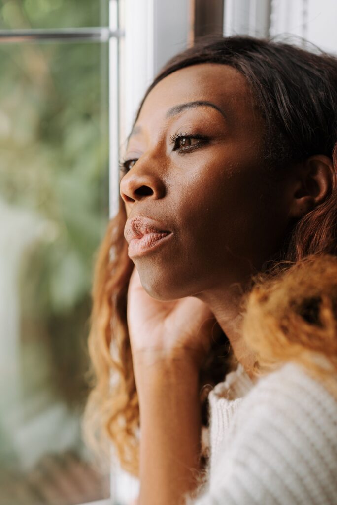 Vrouw kijkt rustig door een raam — algemeen sfeerbeeld bij dagdromen
