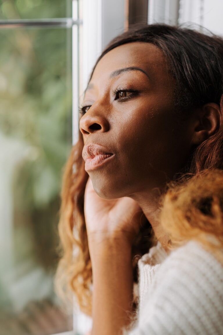 Vrouw kijkt rustig door een raam — algemeen sfeerbeeld bij dagdromen